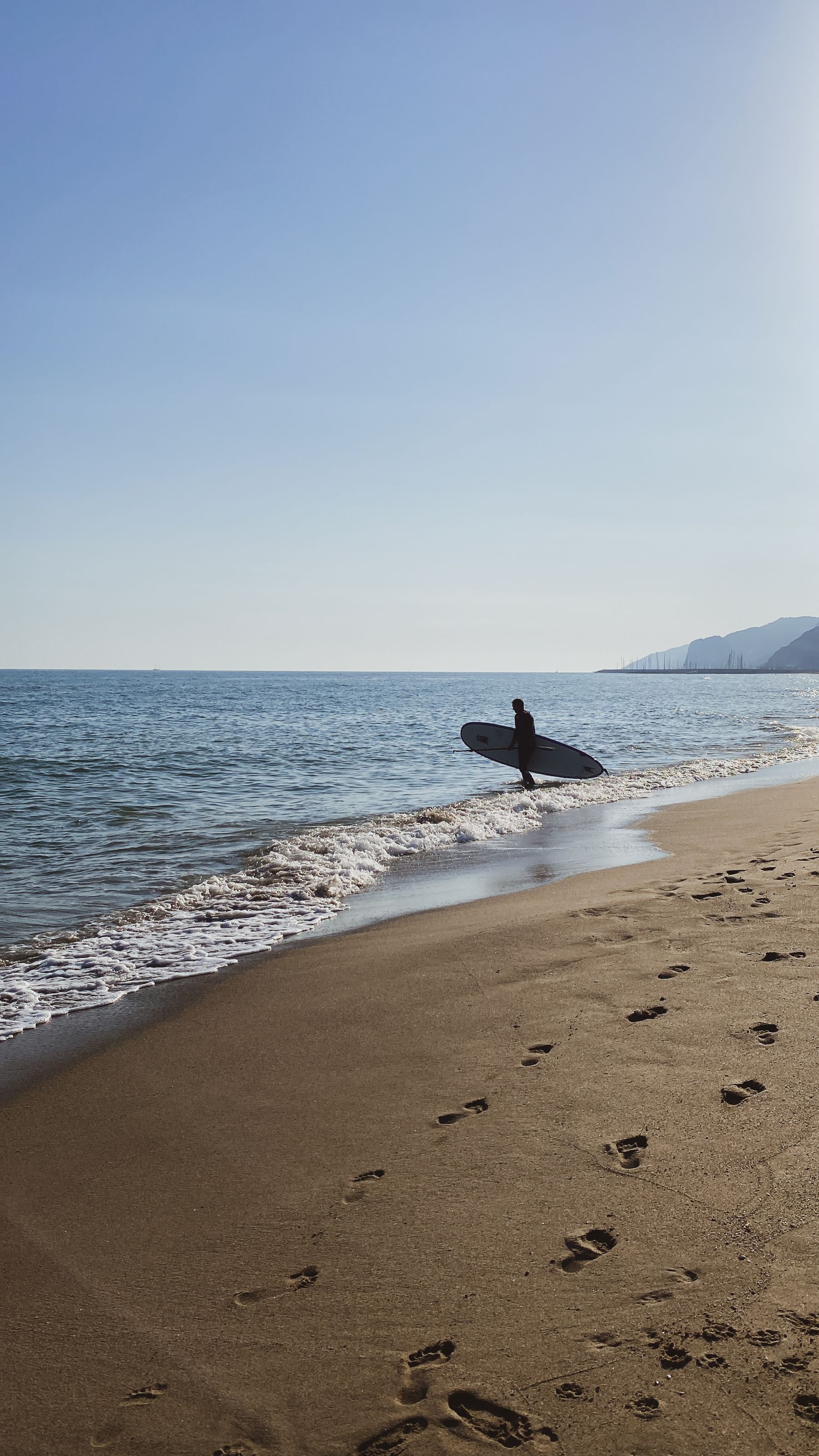 Surfista llevando una tabla en una playa de Barcelona